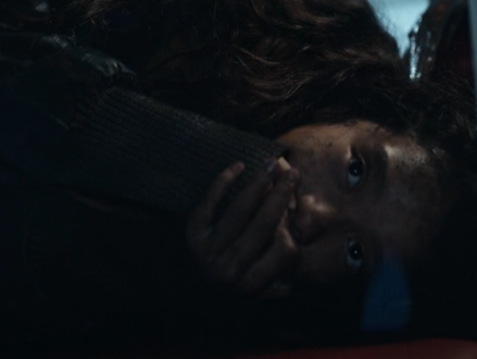 A girl hiding and covering her mouth so she won't make a noise