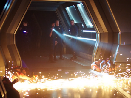 A rescue party exploring dark corridors with mangled bodies and sparks all around