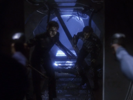 Two people holding phase pistols at approaching zombie-like humanoids