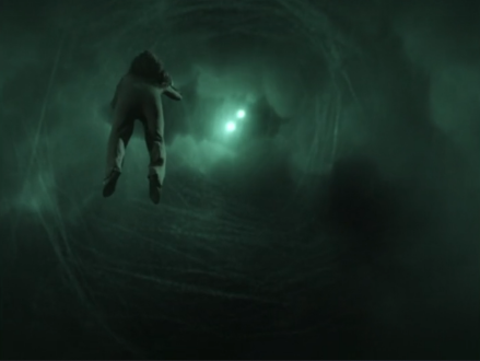 Troi floating in a hazy green fog with two bright lights in the distance