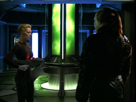 Seven of Nine, holding a phaser rifle at an alien in front of the warp core, which has turned green
