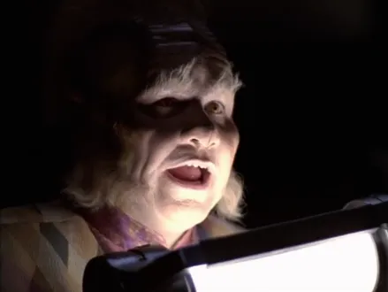 Neelix in a dark room holding up a camping light to his face