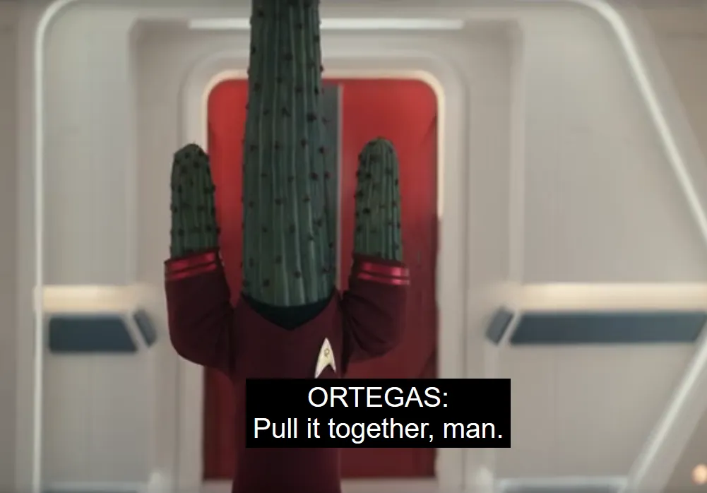 A cactus wearing a red Starfleet uniform, with closed-captioning that says 'ORTEGAS: Pull it together, man.'