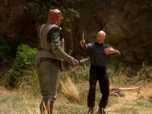 Picard and the Tamarian captain holding knives and discussing strategy on the surface of a planet