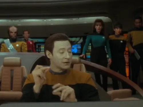 Data improvising a song at the ops console on the bridge as others watch him quizzically