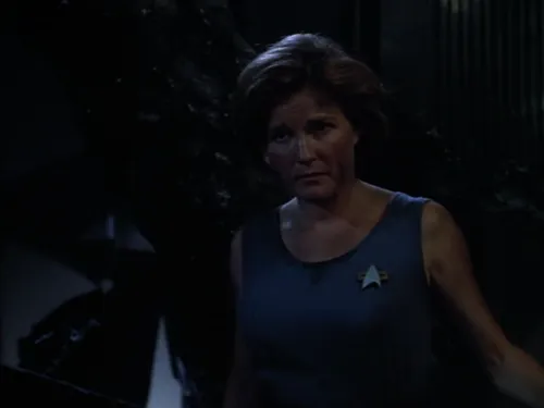 Janeway in a stained uniform with tousled hair and burn marks on her arms and face