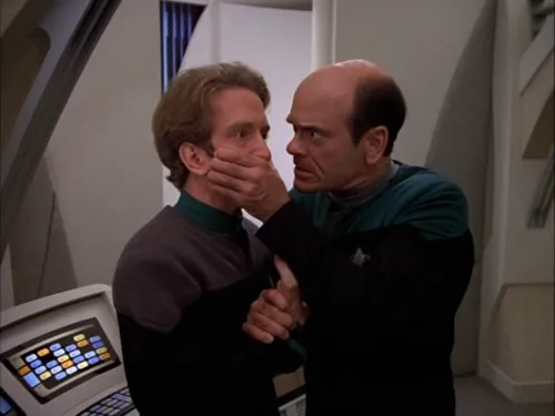 The Doctor covering the mouth of the EMH Mark II to keep him quiet