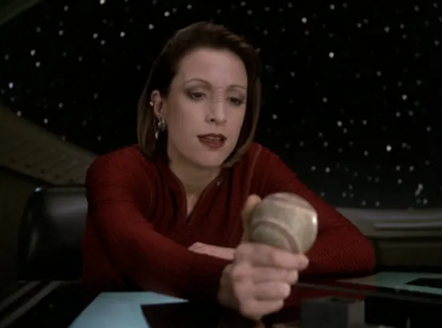 Kira in the station commander's office, holding Sisko's baseball