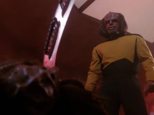 Worf standing over a defeated Duras, who has a bat'leth plunged into his chest