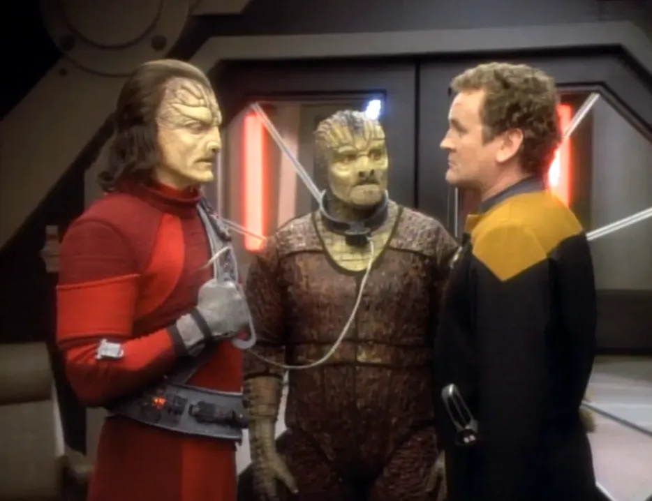 O'Brien with an alien holding a leash around another alien's neck