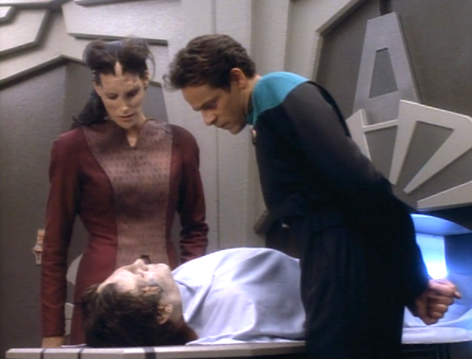 Bashir and an alien standing over a body in the morgue