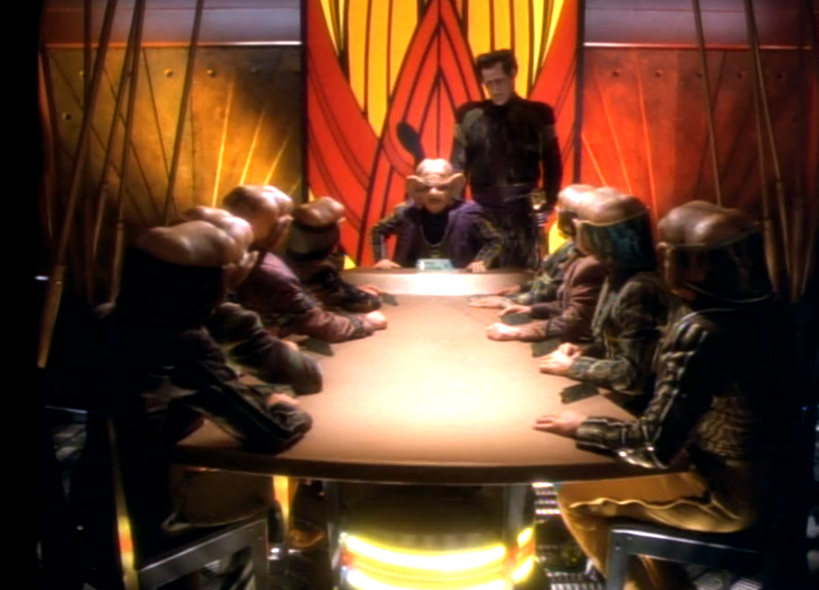 The Grand Nagus sitting the head of a conference table surrounded by other Ferengi