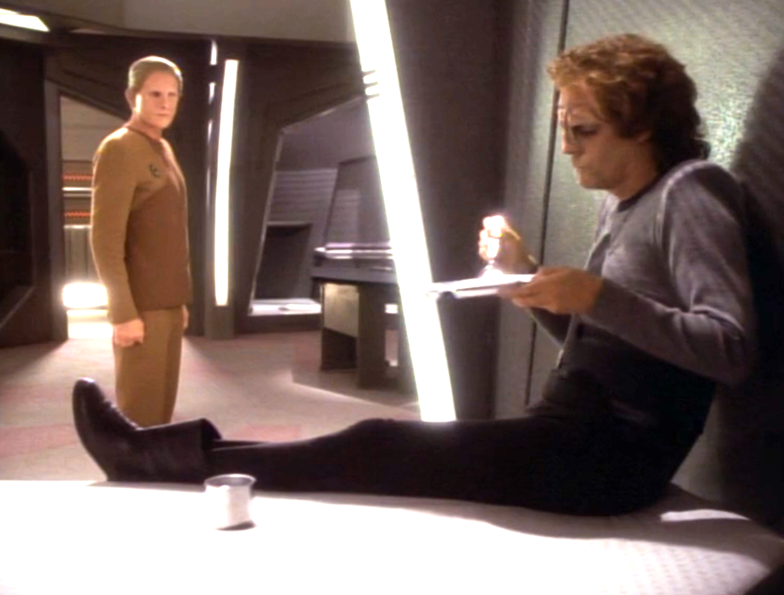 Odo observing a man in a holding cell as he eats