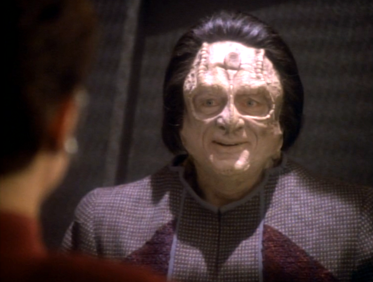 A Cardassian smiling at Kira from inside his holding cell