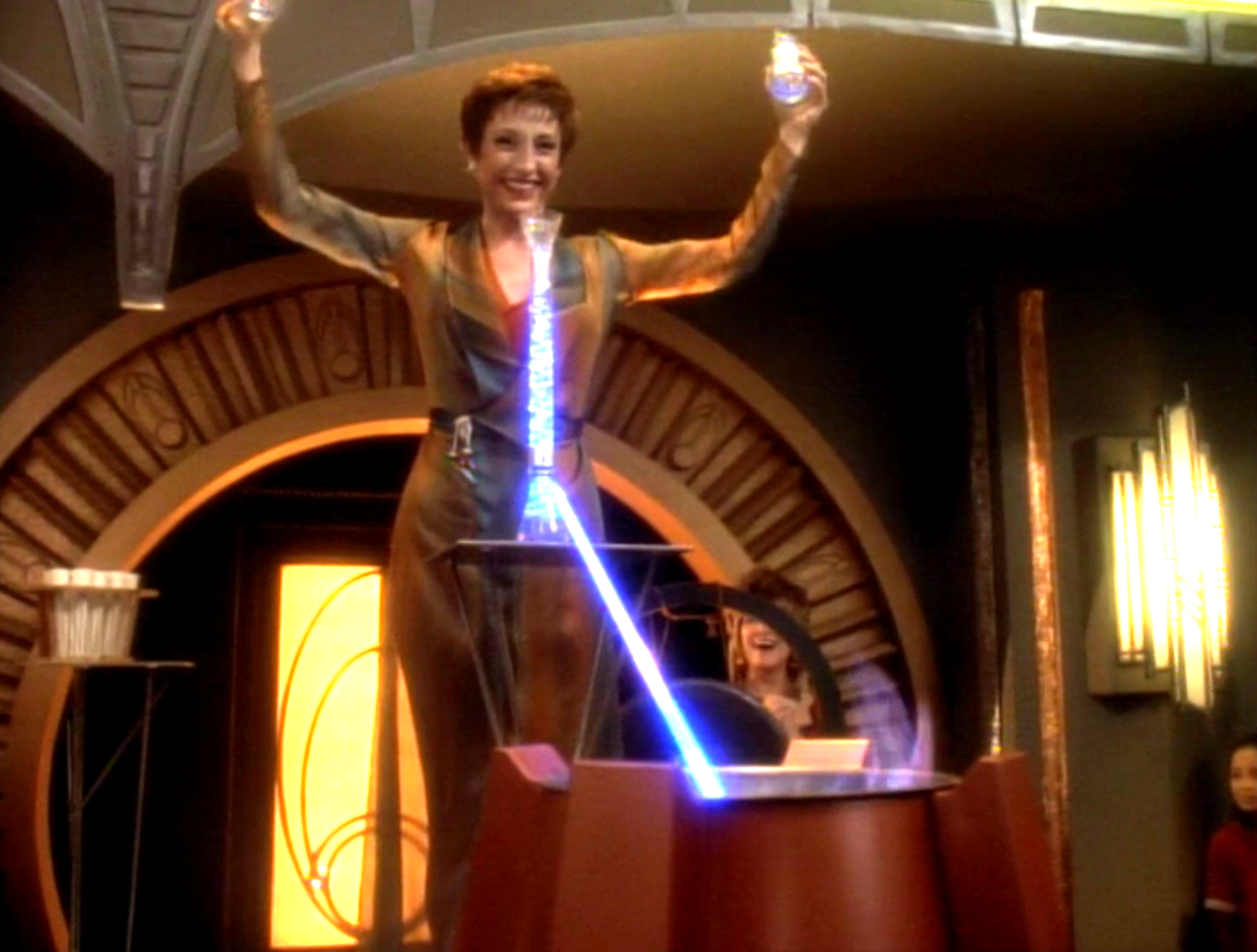 Kira presenting in front of the Bajoran shrine with a smile and her arms over her head