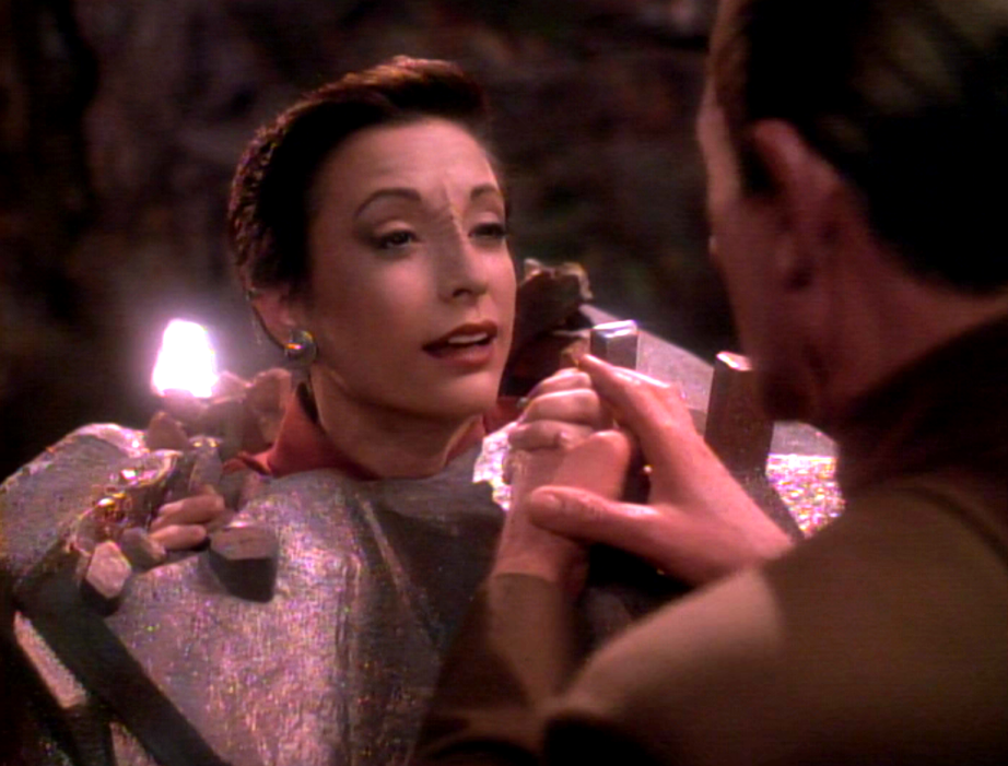 Odo holding hands with Kira, who is trapped in a cocoon of stone