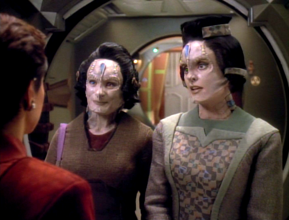 Two Cardassians smiling as are greeted by Kira