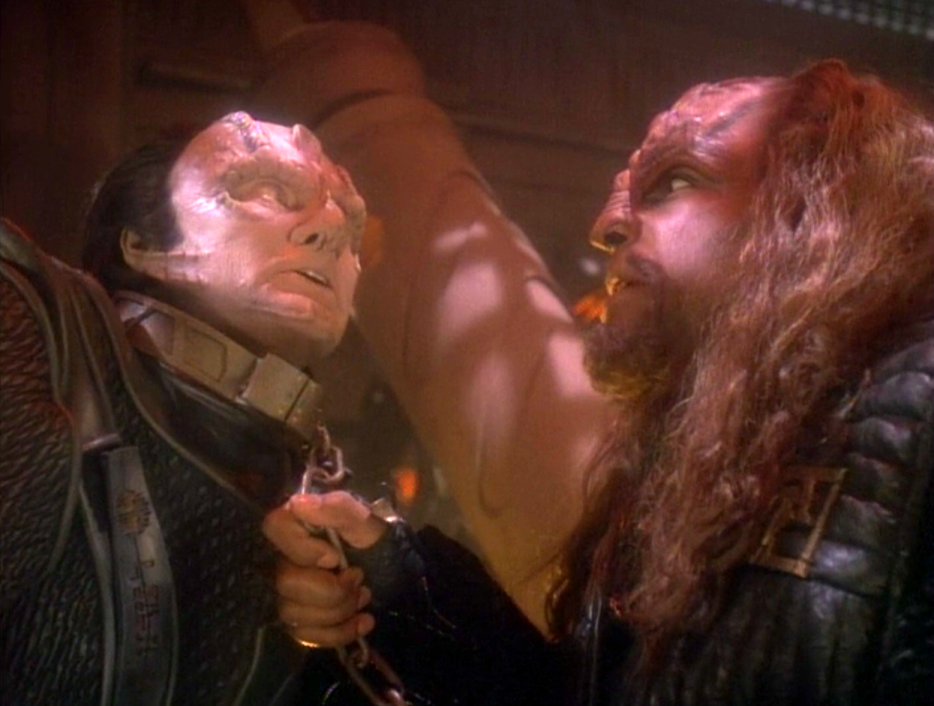 Worf holding a leash around Garak's neck