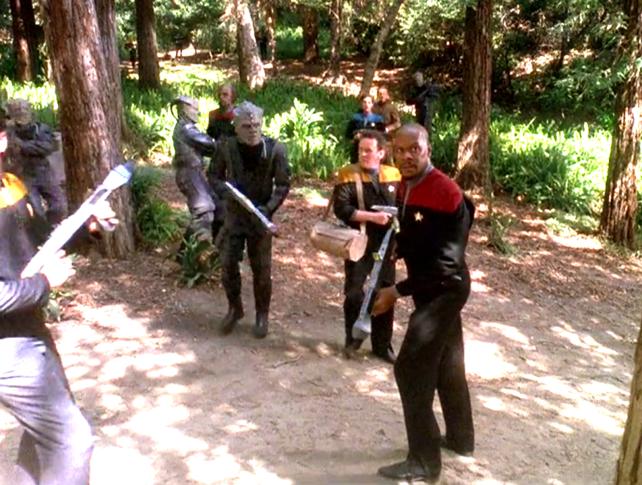 Sisko, his crew, and several Jem'Hadar carrying weapons through a forest