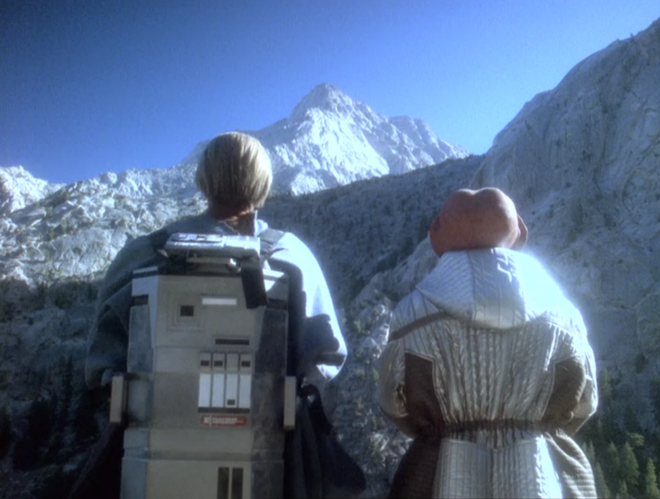 Odo and Quark staring up at a distant mountain peak