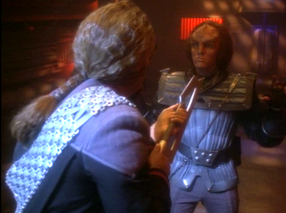 Worf holding a young Klingon at bay with a blade