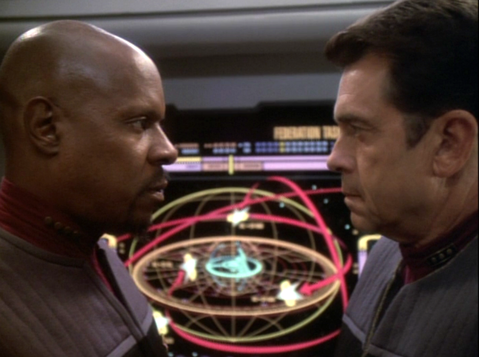 Sisko and Admiral Ross staring eye-to-eye in front of a computer screen depicting a plan to retake DS9