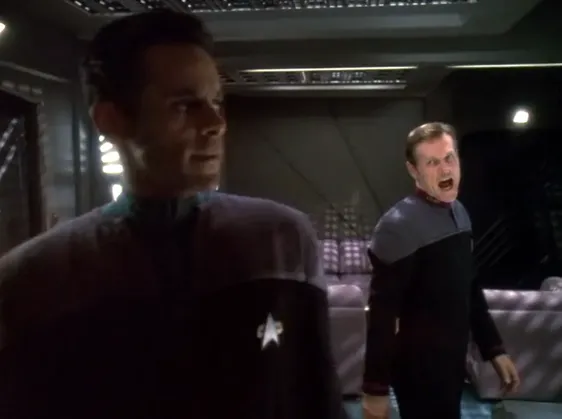 Bashir walking away as another Starfleet officer yells at him