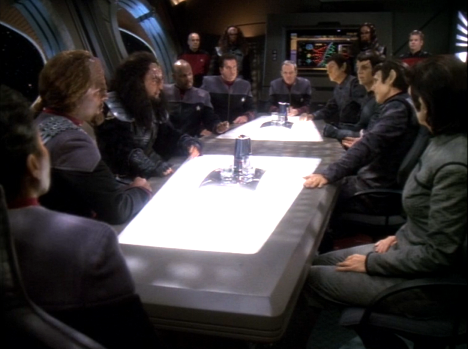 A delegation of Humans, Klingons, and Romulans sitting around a conference table