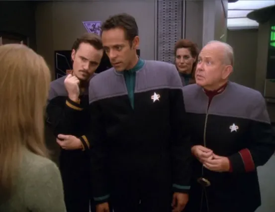 Bashir and three others in Starfleet uniforms discussing treatment for a patient