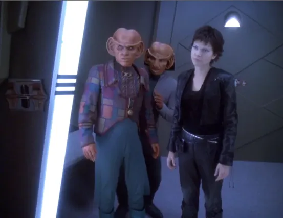 Ezri, clad in all black, standing in a holding cell with Quark and Rom