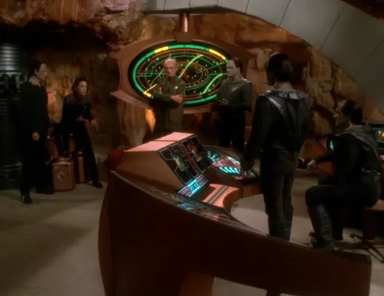 Garak, Kira, Odo, and Damar discussing strategy in an underground resistance base