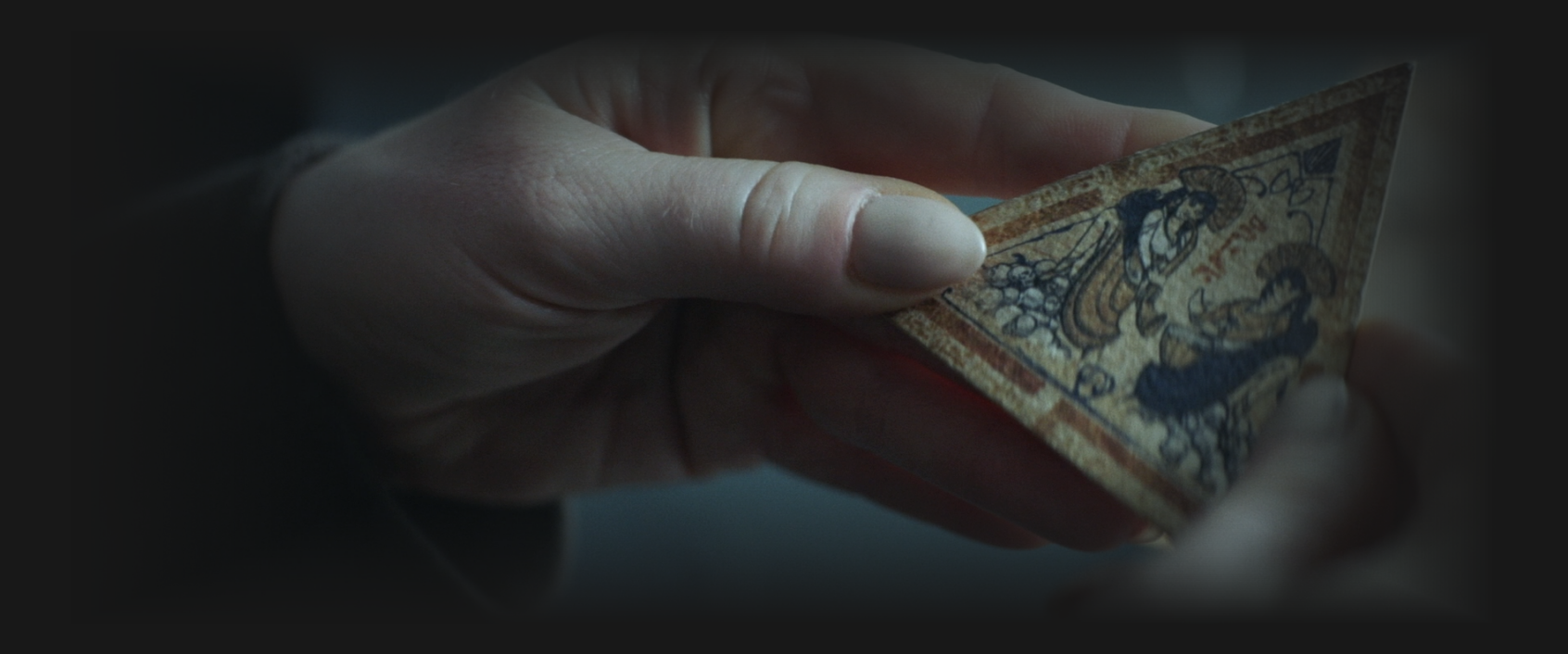 Hands holding a triangular puzzle piece featuring a drawn image of twin sisters