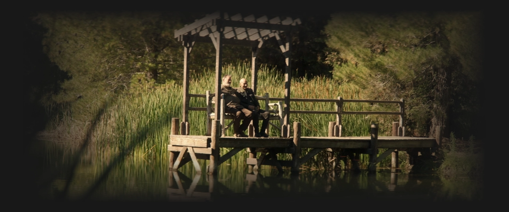 Picard and Riker sitting on a bench on a short pier on a lake