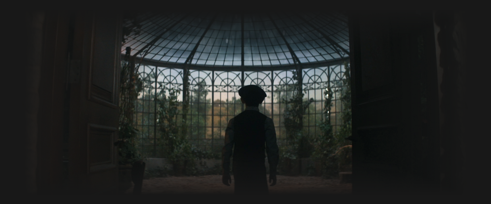 A young boy with a beret entering a large solarium
