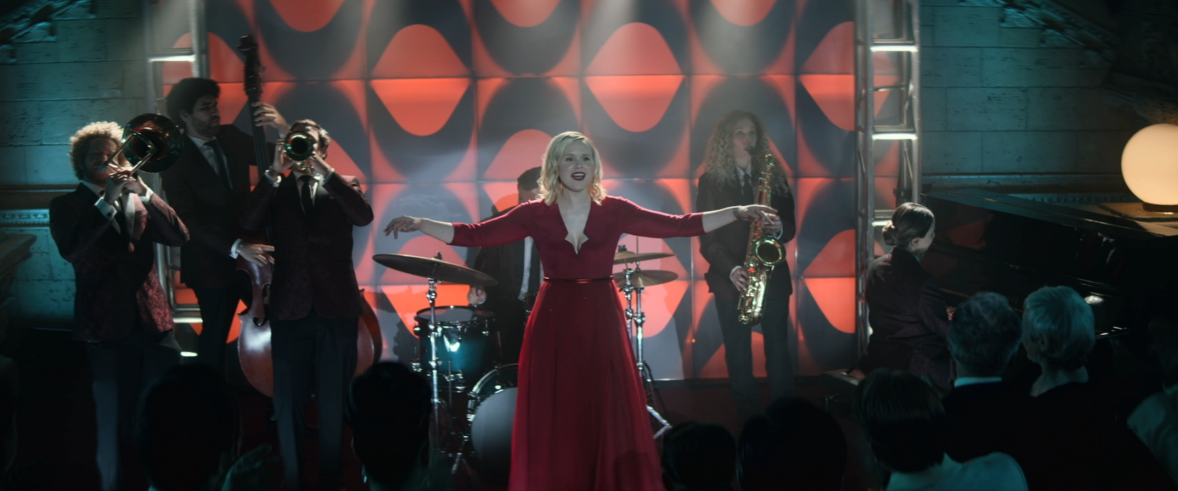 Dr. Jurati singing a song in a red dress with a small band behind her