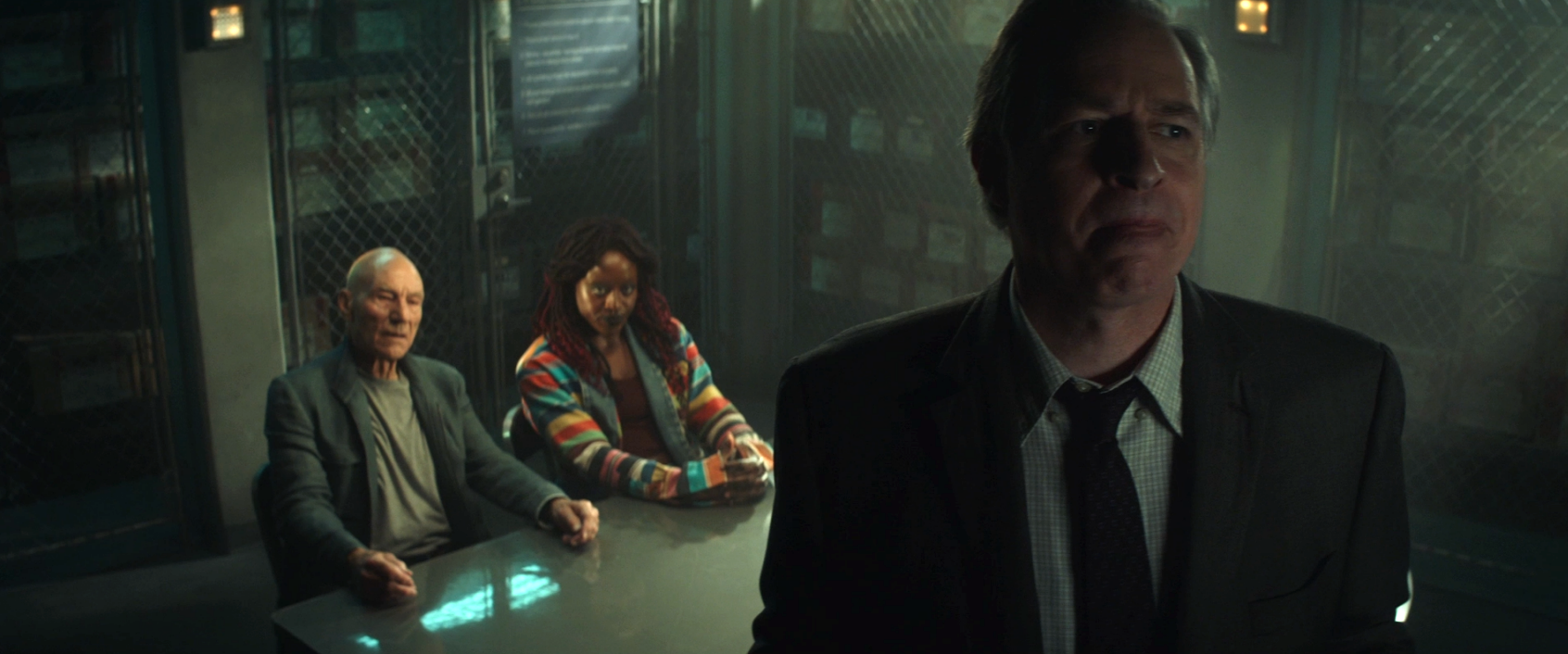 FBI Agent Wells considering his next move in an interrogation room with Picard and Guinan