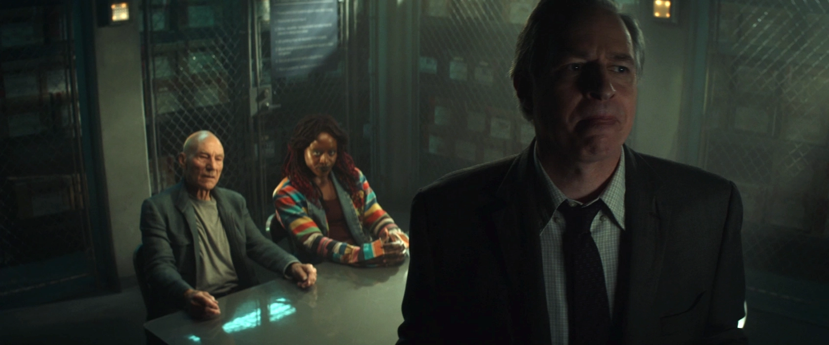 FBI Agent Wells considering his next move in an interrogation room with Picard and Guinan