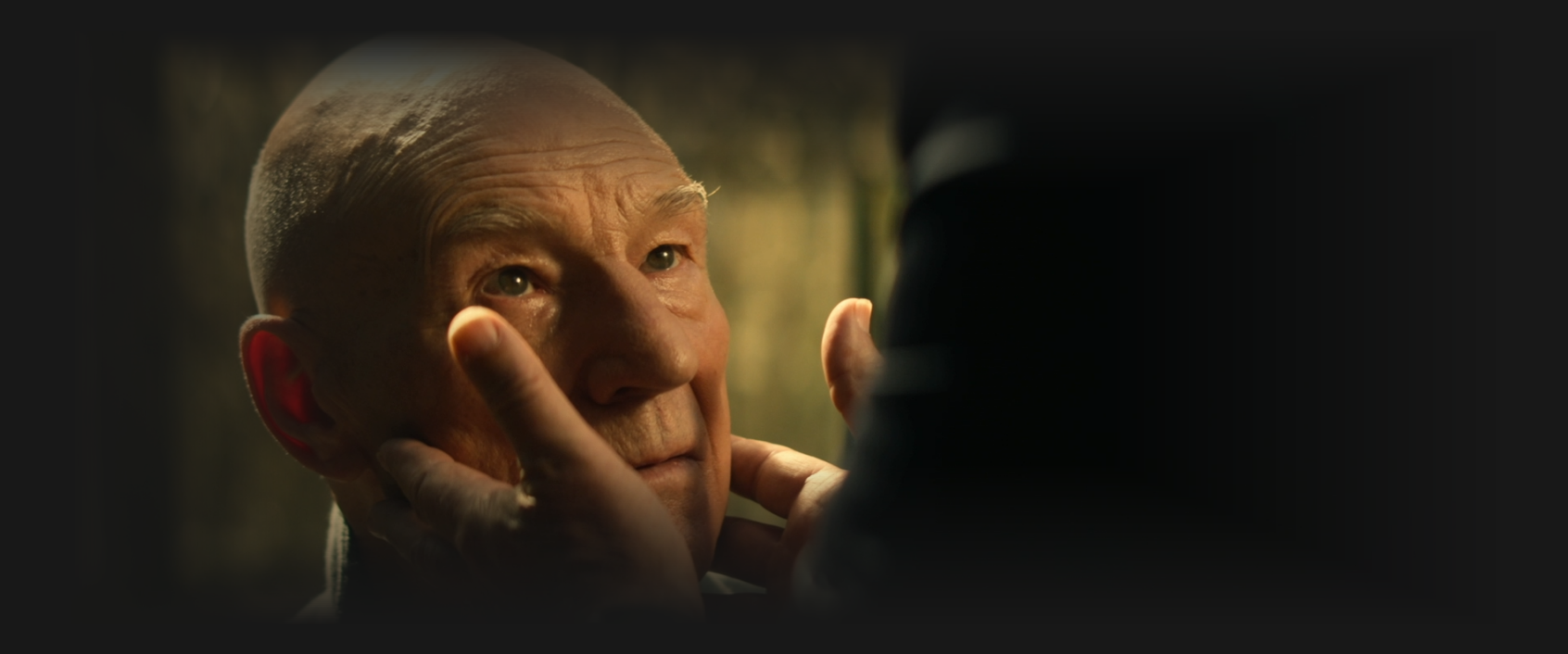 Picard looking up at Q as Q touches Picard's face gently