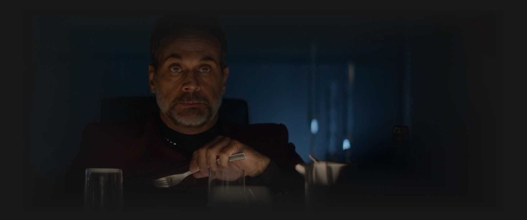Captain Shaw at a dinner table looking annoyed