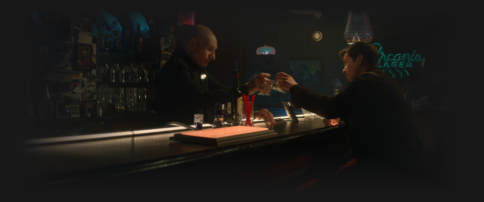 Picard and Jack clink their glasses as they share a drink at the holographic bar