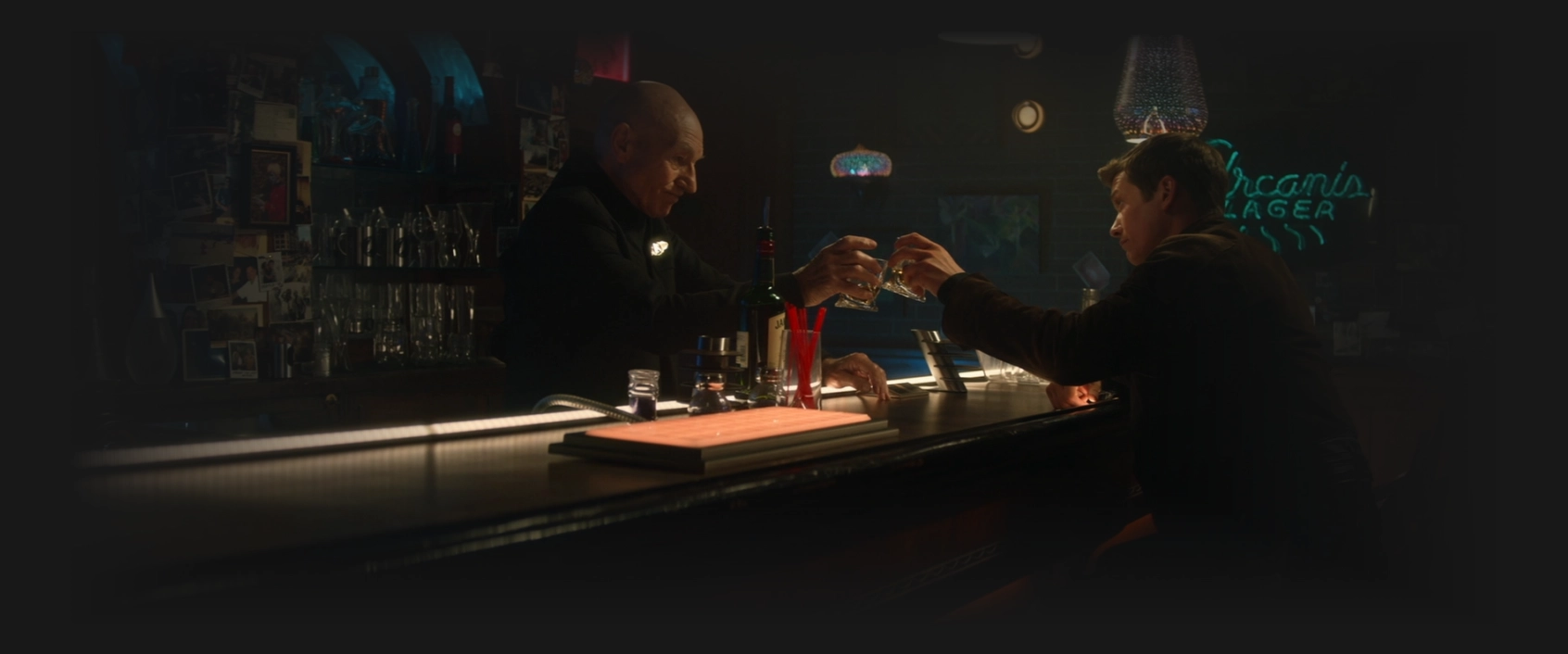 Picard and Jack clink their glasses as they share a drink at the holographic bar