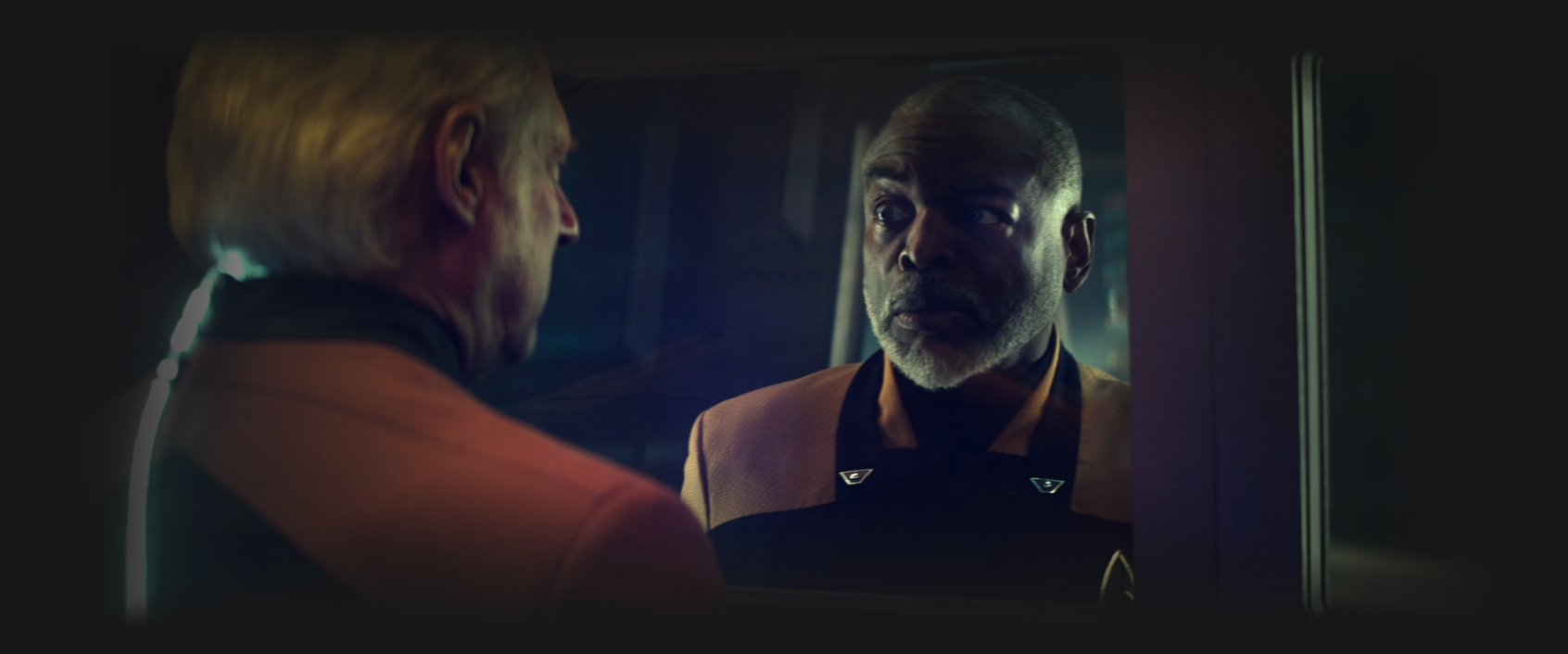 Geordi and the Data/Lore android on opposite sides of a sealed door, looking at each other through a window