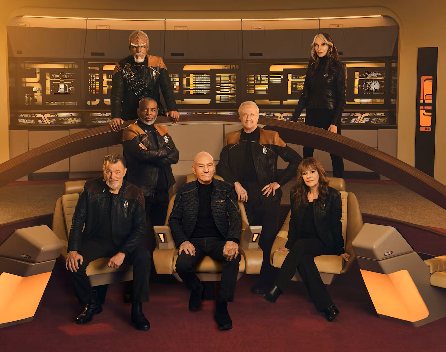 Actors Michael Dorn, Gates McFadden, LeVar Burton, Brent Spiner, Jonathan Frakes, Patrick Stewart, and Marina Sirtis, posing for a cast photo on the set of the Enterprise-D bridge