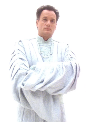 Q, in white robes, standing alone in a white void
