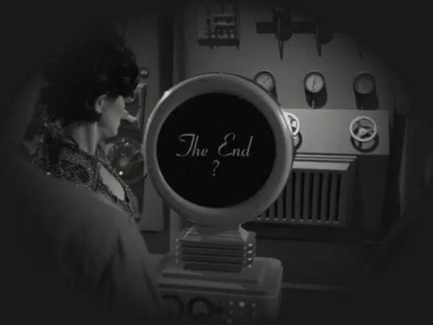 A black-and-white photo of a 50s-style sci-fi scene with a circular screen that bears the words 'The End' with a question mark