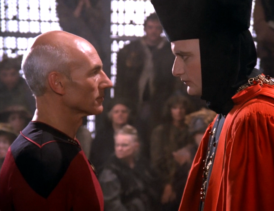 Q, in his judge's robes, staring Picard directly in the eyes