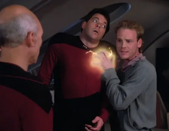 An alien man holding Riker hostage with an electric pulse emanating from his hand