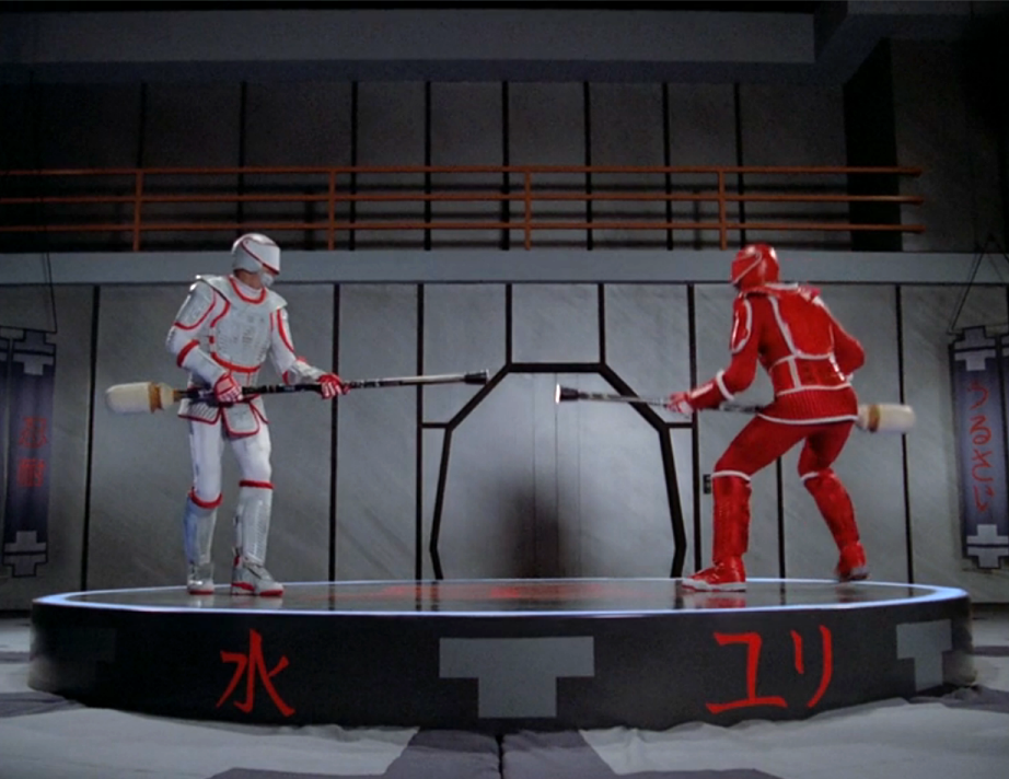 Riker and his father, in red and white protective sports gear, about to do combat
