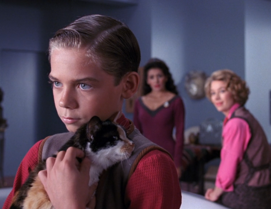 Jeremy Astor holding his cat while Deanna Troi and an apparition of his deceased mother look on
