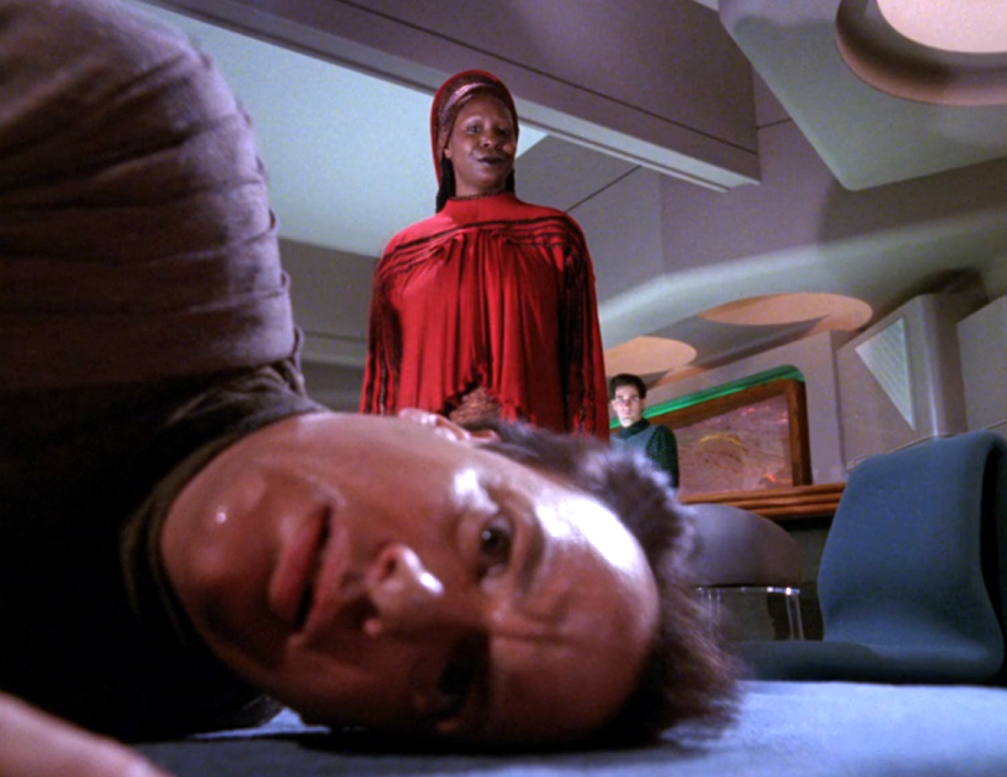 Guinan standing over a frightened-looking Q